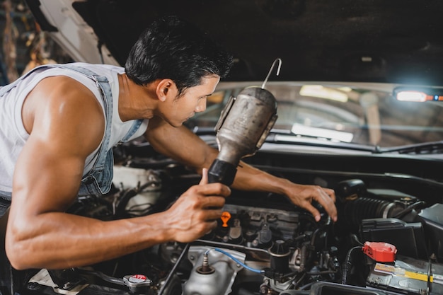 Mechanik pracujący i sprawdzający serwis techniczny silników samochodowych wykonujący prace w branży motoryzacyjnej w celu konserwacji lub naprawy samochodu w warsztacie samochodowym biznes przemysłowy silnik samochodowy