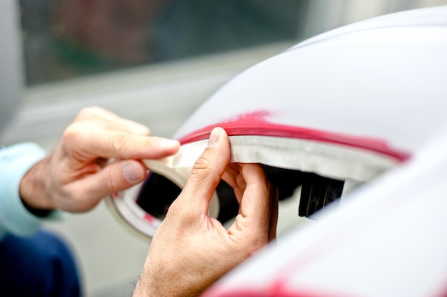 Mechanik przygotowuje samochód do malowania zabezpieczając krawędzie