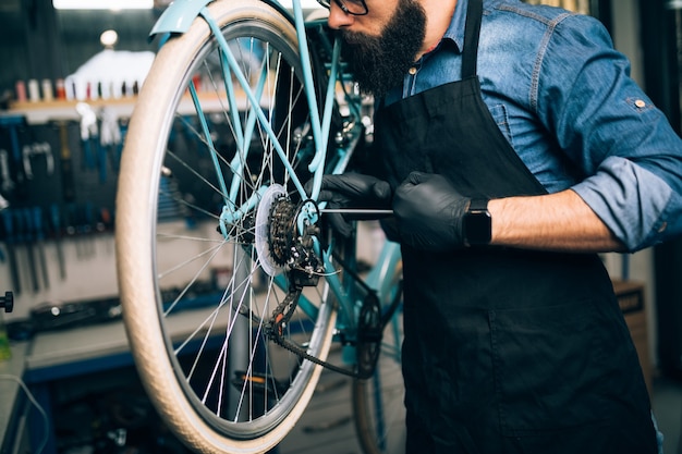 Mechanik rowerowy młody broda naprawa rowerów w warsztacie.