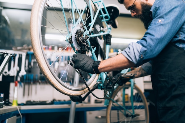 Mechanik rowerowy młody broda naprawa rowerów w warsztacie.