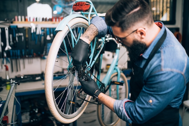 Mechanik rowerowy młody broda naprawa rowerów w warsztacie.