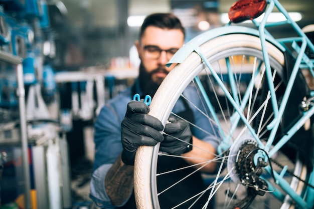 Mechanik rowerowy młody broda naprawa rowerów w warsztacie.