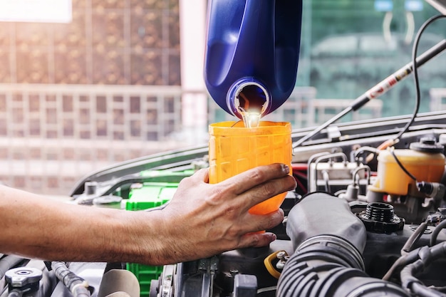 Zdjęcie mechanik samochodowy napełnia olej silnikowy samochodu w centrum naprawy samochodów.