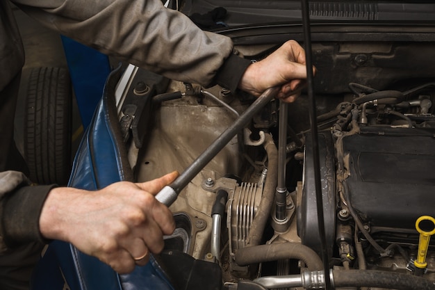 Mechanik samochodowy odkręca mocowanie silnika, aby wymienić pasek rozrządu