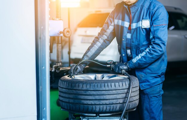 Mechanik Samochodowy Sprawdzający Ciśnienie W Oponach Samochodowych Na Usuniętym Kole W Garażu Samochodowym