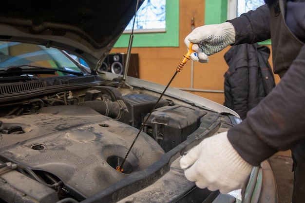 Mechanik samochodowy sprawdzający poziom oleju w warsztacie mechanicznym