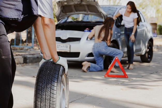 Mechanik serwisowy na miejscu zmieniający oponę młodej kobiety złapał gumę podczas podróży