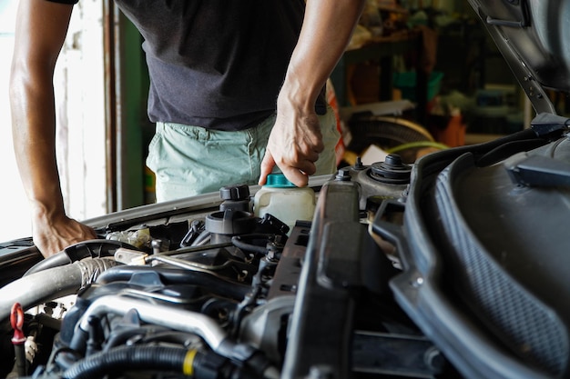 Mechanik sprawdza zbiornik wyrównawczy za pomocą różowego płynu niezamarzającego Poziom płynu chłodzącego pojazdu w samochodowych częściach układu chłodnicy