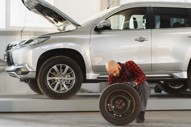 Mechanik Trzymający Oponę W Warsztacie Naprawczym