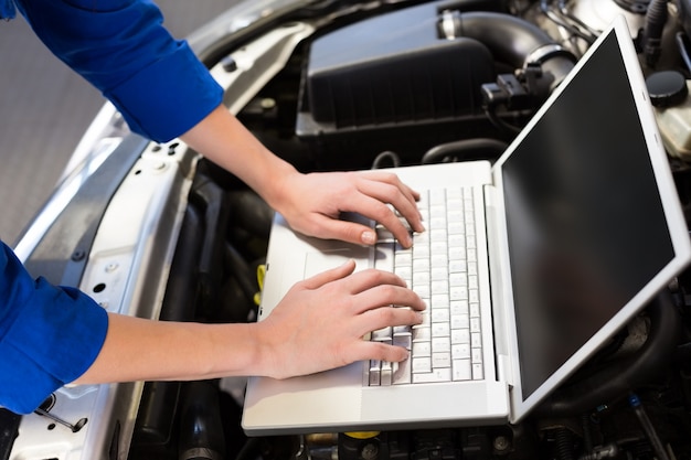 Mechanik używa laptop na samochodzie przy remontowym garażem