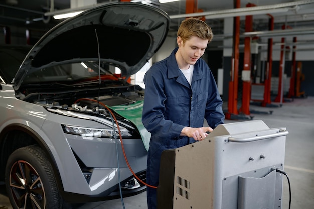 Mechanik w garażu samochodowym wykonujący serwis klimatyzacji lub klimatyzacji
