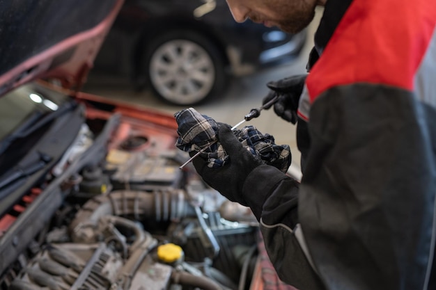 Mechanik w rękawicach w odzieży roboczej przygotowujący narzędzie do naprawy samochodu