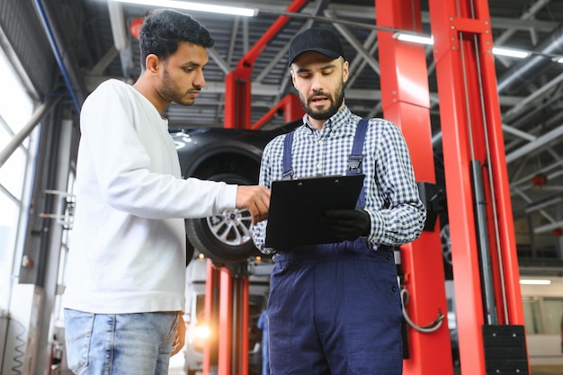 Mechanik w serwisie samochodowym rozmawia z indyjskim właścicielem samochodu Koncepcja serwisu samochodowego