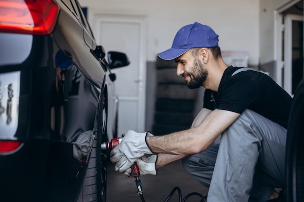 Mechanik w serwisie samochodowym zmieniający opony