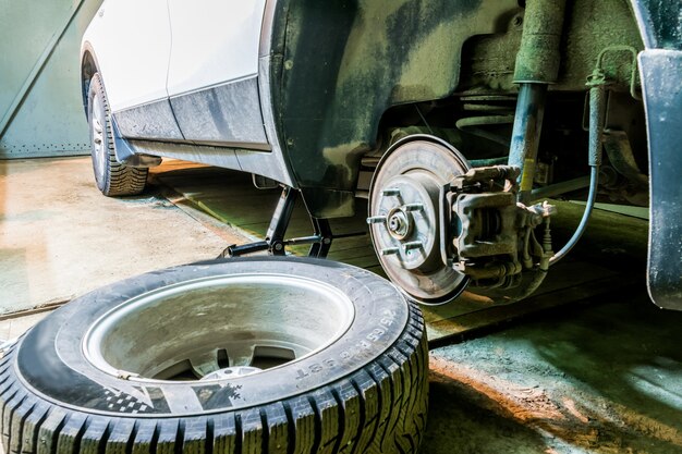 Mechanik zmienia koło samochodu w garażu. Mężczyzna wymienia oponę. Serwis opon. Montaż opon.