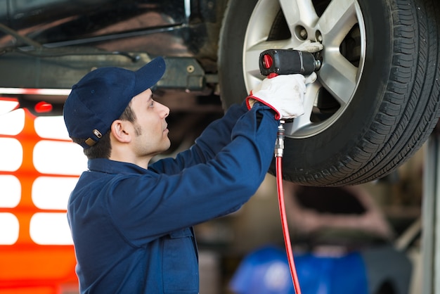 Mechanik zmienia samochodowego koło w auto remontowym sklepie