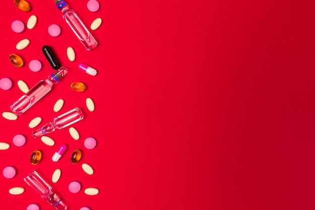 Medetsyn tło z ampułek do wstrzykiwań tabletki i kapsułki na czerwonym tle