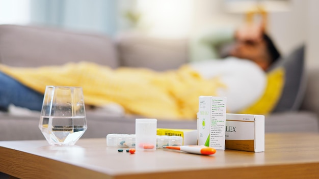 Zdjęcie medycyna chora i mężczyzna na kanapie z tabletkami na wirusa alergii lub przeziębienie opieka zdrowotna covid i afrykański mężczyzna na kanapie z lekami na grypę lub antybiotykami na chorobę