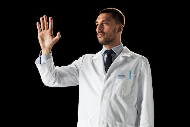 medycyna, nauka, opieka zdrowotna i koncepcja ludzi - lekarz lub naukowiec w białym płaszczu dotykający czegoś niewidzialnego na czarnym tle