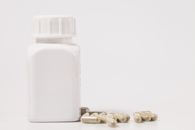 Zdjęcie medyczne kapsułki leku z białą plastikową butelką