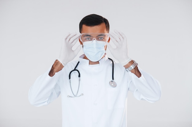 Medyk w mundurze Młody przystojny mężczyzna stojący w pomieszczeniu na białym tle