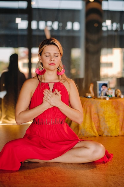 Medytacja i koncentracja kobieta w czerwonej sukience siedząca na podłodze z zamkniętymi oczami praktykuje medycynę w pomieszczeniu Spokój i relaks