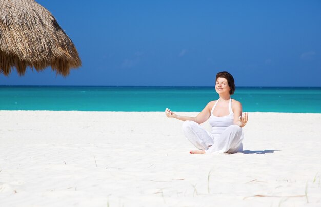 medytacja szczęśliwa kobieta w pozycji lotosu na plaży