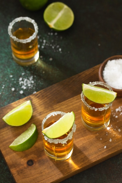 Meksykańska złota tequila z limonką i solą na ciemnym kamiennym tle