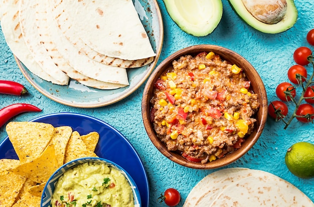 Meksykańskie jedzenie wymieszaj nachos, fajitas, tortilla, guacamole i sosy salsa i składniki na niebieskiej powierzchni. Widok z góry