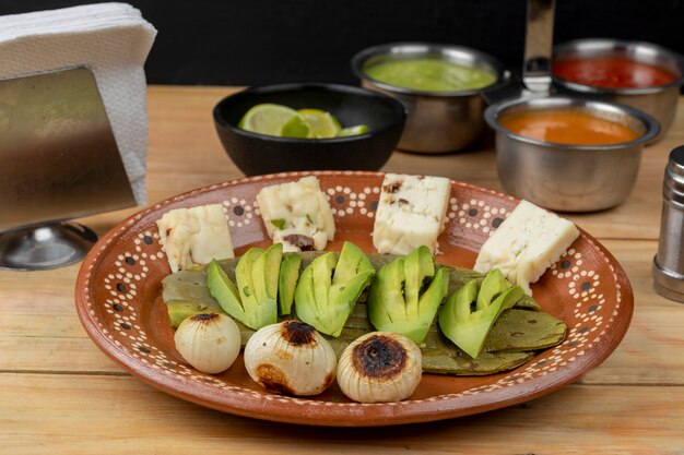 Meksykańskie jedzenie z awokado z nopalem i cebulą podane w glinianym talerzu na drewnianym stole