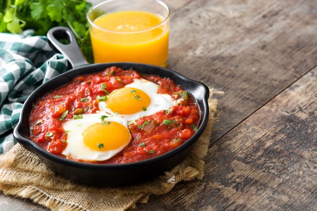 Meksykańskie śniadanie Huevos rancheros na żelaznej patelni na drewnianym stole