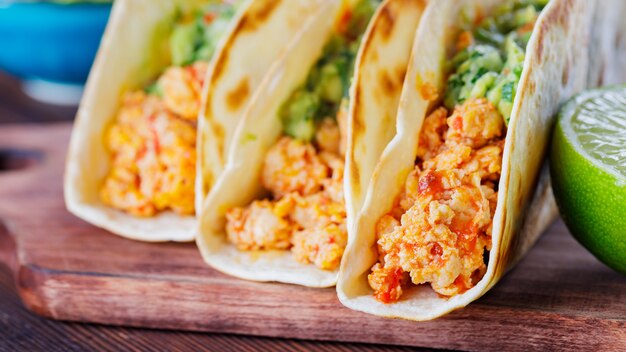 Meksykańskie Tacos Ze Smażonym Mielonym Kurczakiem I Sosem Guacamole Na Drewnianych Deskach. Tacos, Guacamole I Limonka Na Drewnianym Tle. Kuchnia Meksykańska