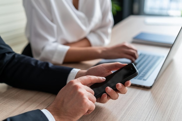 Menadżerowie Biur Płci Męskiej I żeńskiej Siedzą Przy Stole Z Laptopem Mężczyzna Trzymający Telefon W Ręku Kobieta Kierownik Z Pisaniem Na Laptopie Koncepcja Pracy Zespołowej