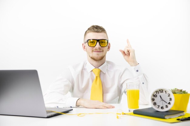 Menedżer w żółtych okularach wskazuje palcem w górę, akcentując żółty słoik z krawatem