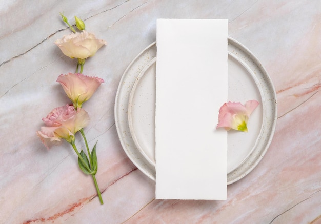 Zdjęcie menu ślubne leżące na ceramicznej talerzu na marmurowym stole ozdobionym kwiatami i wstążkami