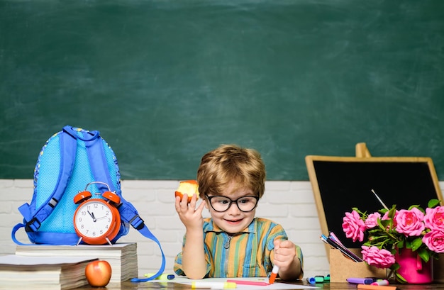 Menu żywności mały uczeń jedzący lunch z jabłkiem w klasie uczeń ze szkoły podstawowej w