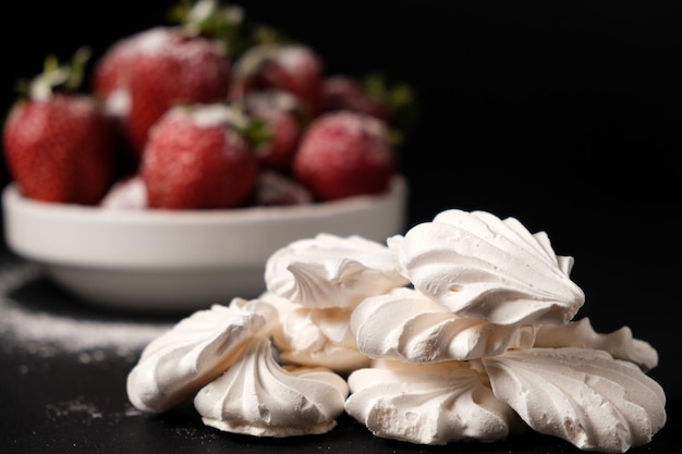 Meringue bliska i truskawki w tabliczce na czarnym tle Desery owocowe