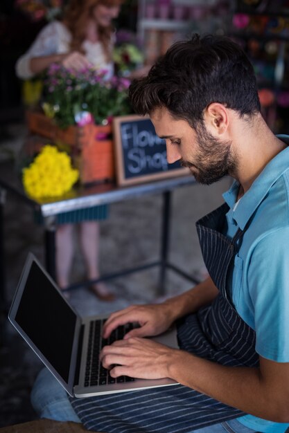 Zdjęcie męska kwiaciarnia siedzi laptop i używa