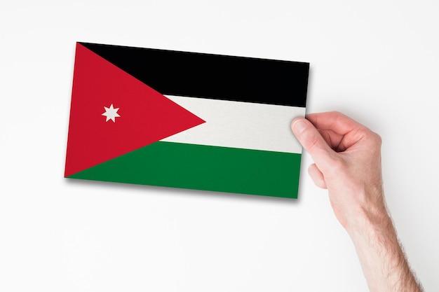 Męska ręka trzyma flagę jordanii