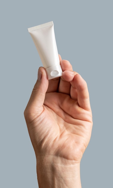 Męska ręka trzyma kremową tubkę makiety puste opakowanie dla kosmetycznego produktu