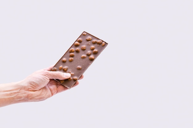 Męska ręka trzyma tabliczkę czekolady na szaro