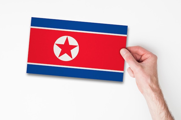 Męska ręka trzymająca flagę Korei Północnej