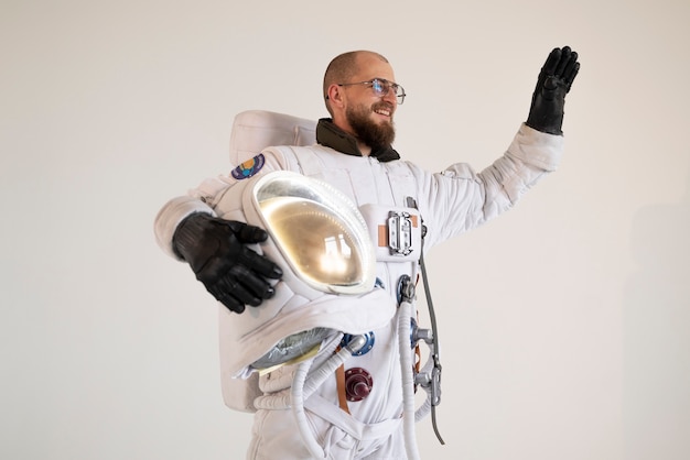 Męski astronauta trzymający hełm i machający