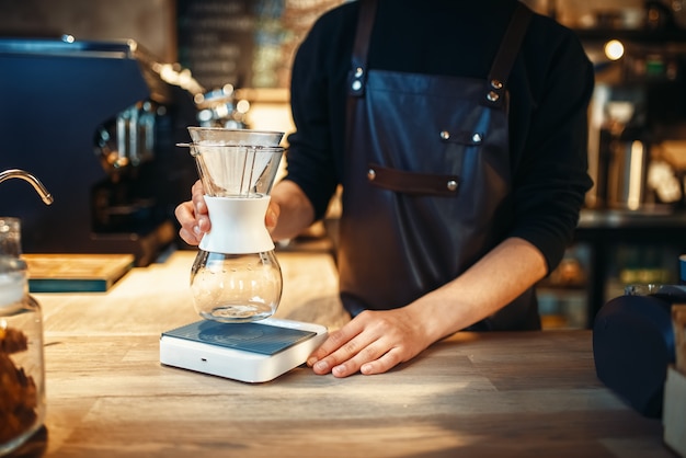 Męski barista stawia na kuchence szklankę wody