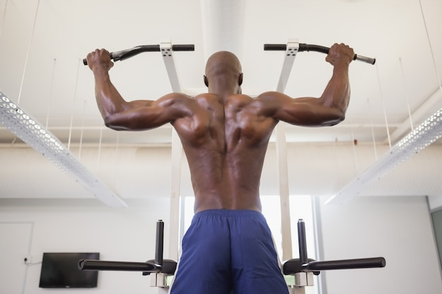 Męski ciało budowniczy robi ciągnieniu podnosi przy gym