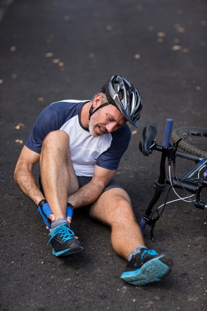 Męski Cyklista W Bólu Trzyma Jej Ranną Nogę