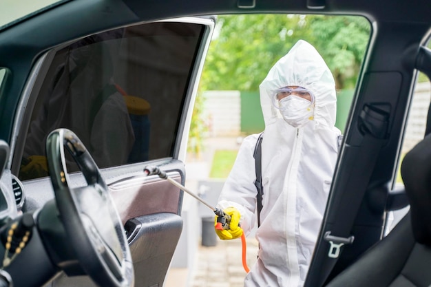 Męski dezynfektor dokonujący dezynfekcji wnętrza samochodu