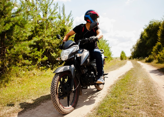 Zdjęcie męski jeździecki motocykl na drodze gruntowej z hełmem