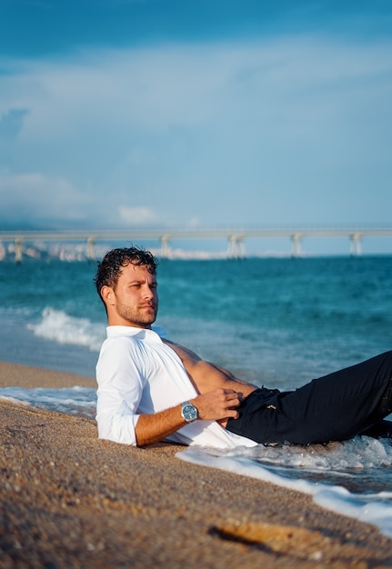 Męski mężczyzna relaksujący się wieczorem na mokrej plaży