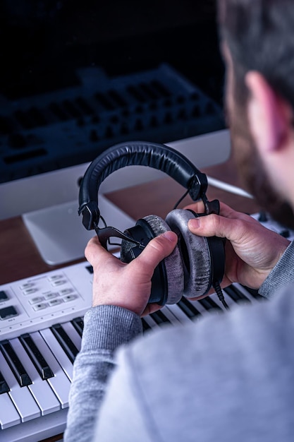 Męski muzyk tworzy muzykę przy użyciu komputera i miejsca pracy muzyków klawiszowych